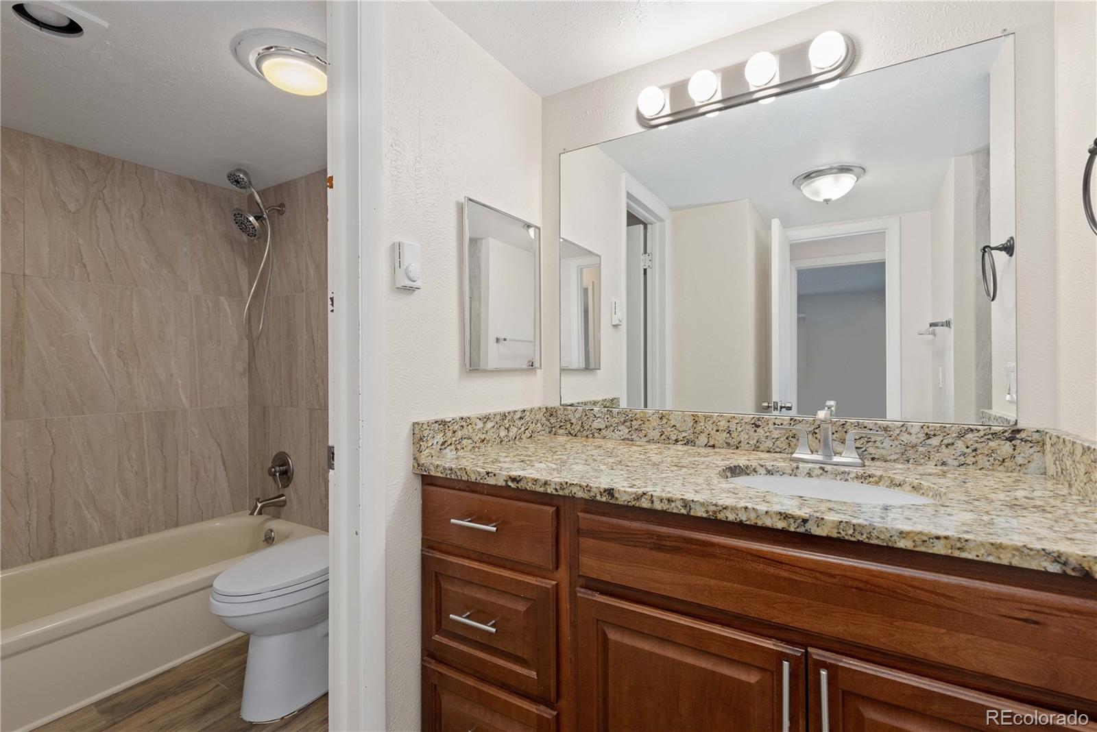 4068 South Atchison Way, Unit 202 Aurora, CO 80014 - Photo 20 of 33 a bathroom with a granite countertop sink toilet mirror and shower