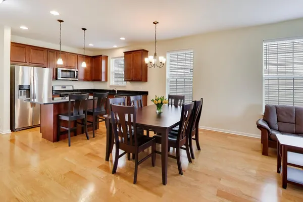 a kitchen with kitchen island a dining table chairs stainless steel appliances and cabinets