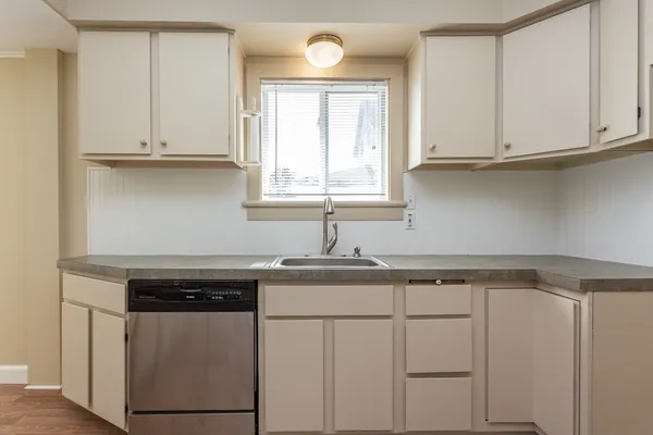 a kitchen with white cabinets and sink
