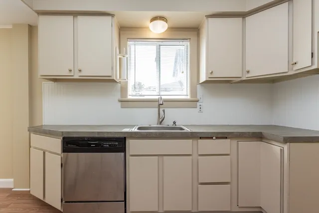 a kitchen with white cabinets and sink