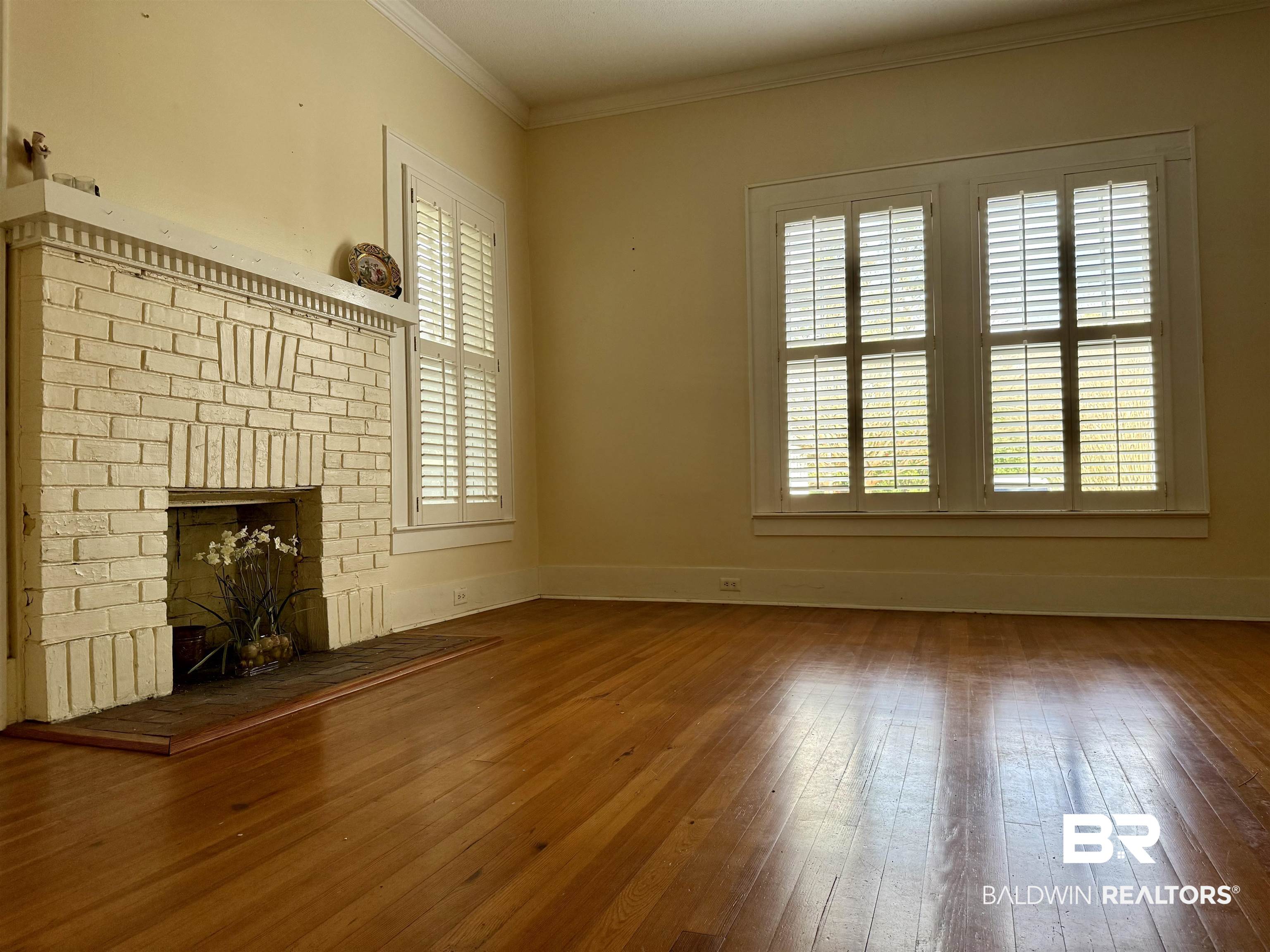 423 Evergreen Avenue Brewton, AL 36426 - Photo 5 of 18 Unfurnished living room with a brick fireplace, crown molding, and hardwood / wood-style floors