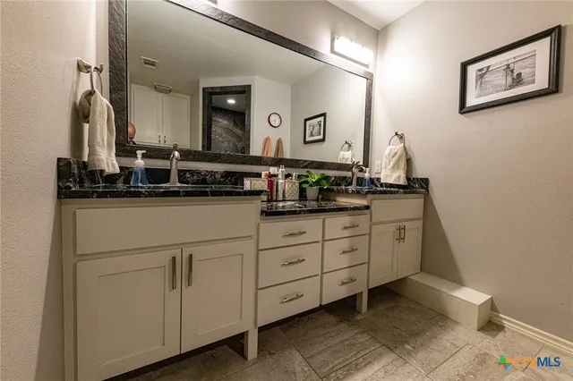 a bathroom with a granite countertop sink and a mirror
