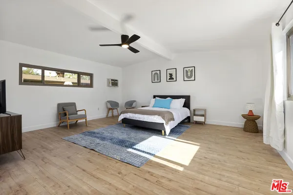 a spacious bedroom with a bed a table and a dresser