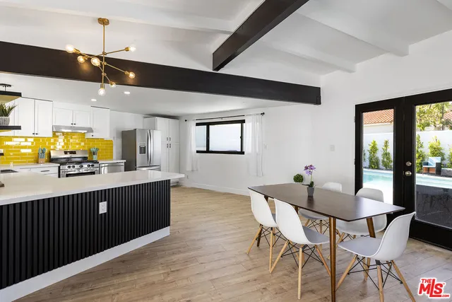 a kitchen with stainless steel appliances kitchen island granite countertop a table chairs and a wooden floor