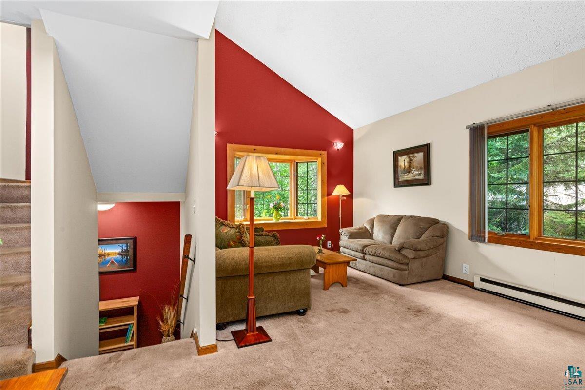 5195 Lavaque Junction Road Hermantown, MN 55811 - Photo 18 of 66 Carpeted living area featuring vaulted ceilings, a prominent accent wall, and wood-framed windows