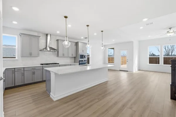 a large kitchen with granite countertop a large counter top a sink stainless steel appliances and cabinets