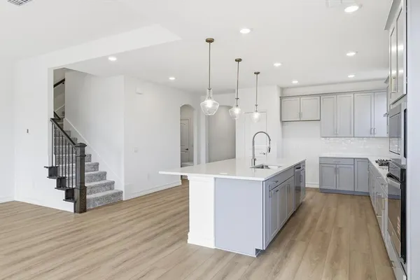 a large kitchen with white cabinets stainless steel appliances and wooden floor