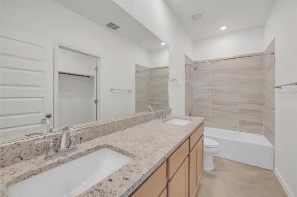 a bathroom with a granite countertop sink a toilet and bathtub