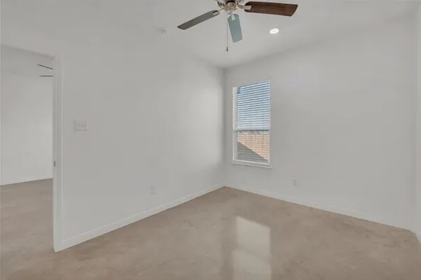 an empty room with a window and a ceiling fan