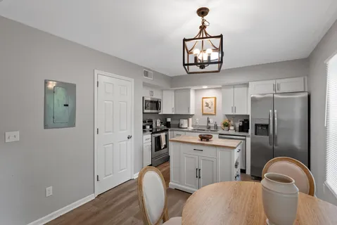 a kitchen with stainless steel appliances granite countertop a sink dishwasher a refrigerator with a dining table and chairs