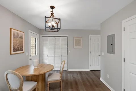 a dining room with wooden floor a chandelier a wooden table and chairs