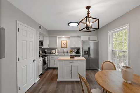 a kitchen with stainless steel appliances granite countertop a stove a sink dishwasher a refrigerator with wooden cabinets and floor