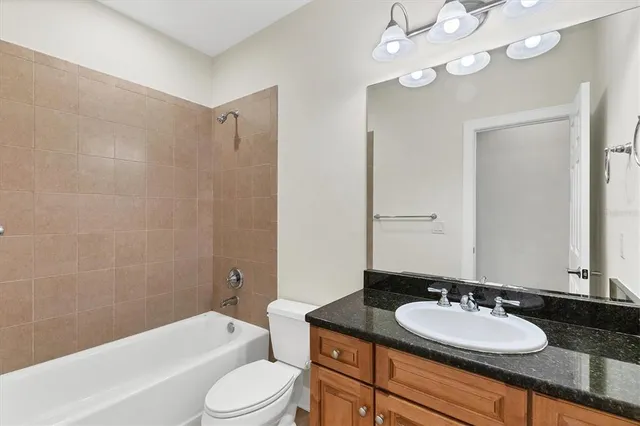 a bathroom with a granite countertop sink a toilet a mirror a bathtub and shower