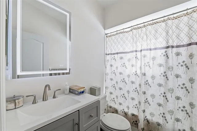 a bathroom with a granite countertop sink a toilet and a mirror