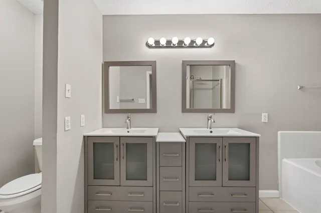 a bathroom with a sink double vanity granite tub and a mirror