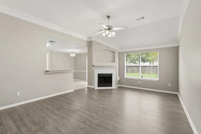 an empty room with wooden floor fireplace and windows