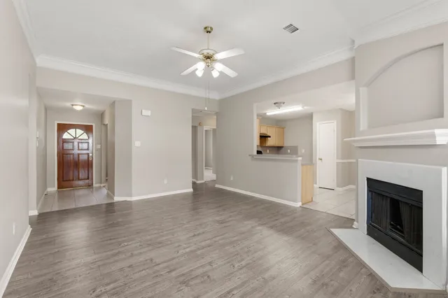 an empty room with wooden floor fireplace and windows