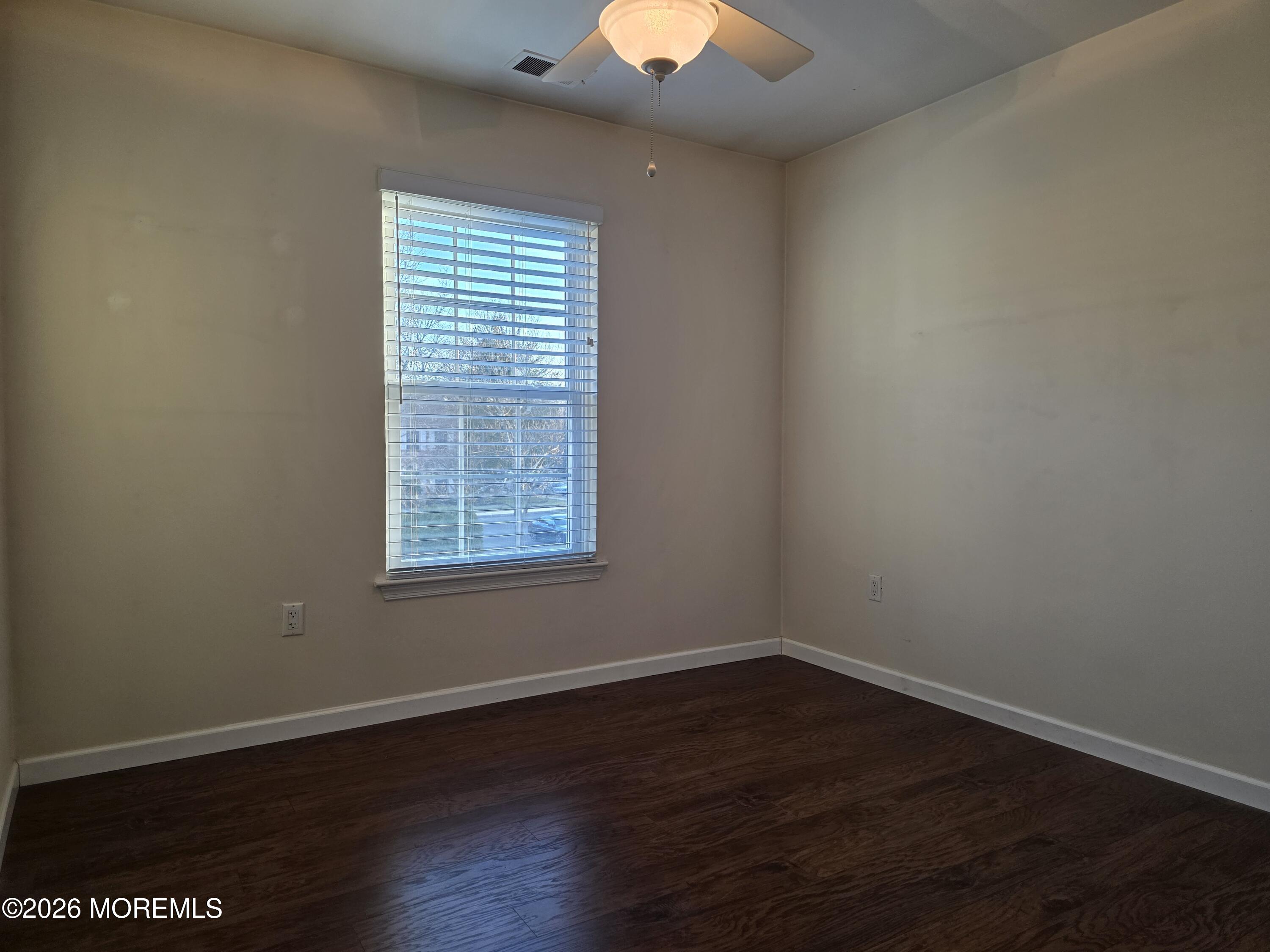 5 Claridge Court, Unit 4 Freehold, NJ 07728 - Photo 12 of 13 a view of an empty room with wooden floor and a window