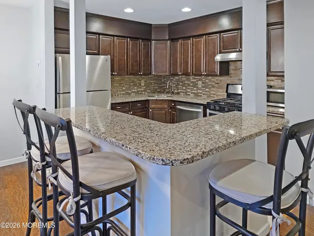a kitchen with stainless steel appliances kitchen island granite countertop a table chairs and a refrigerator