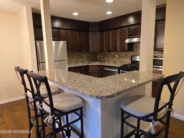 a kitchen with granite countertop a table chairs stove and refrigerator