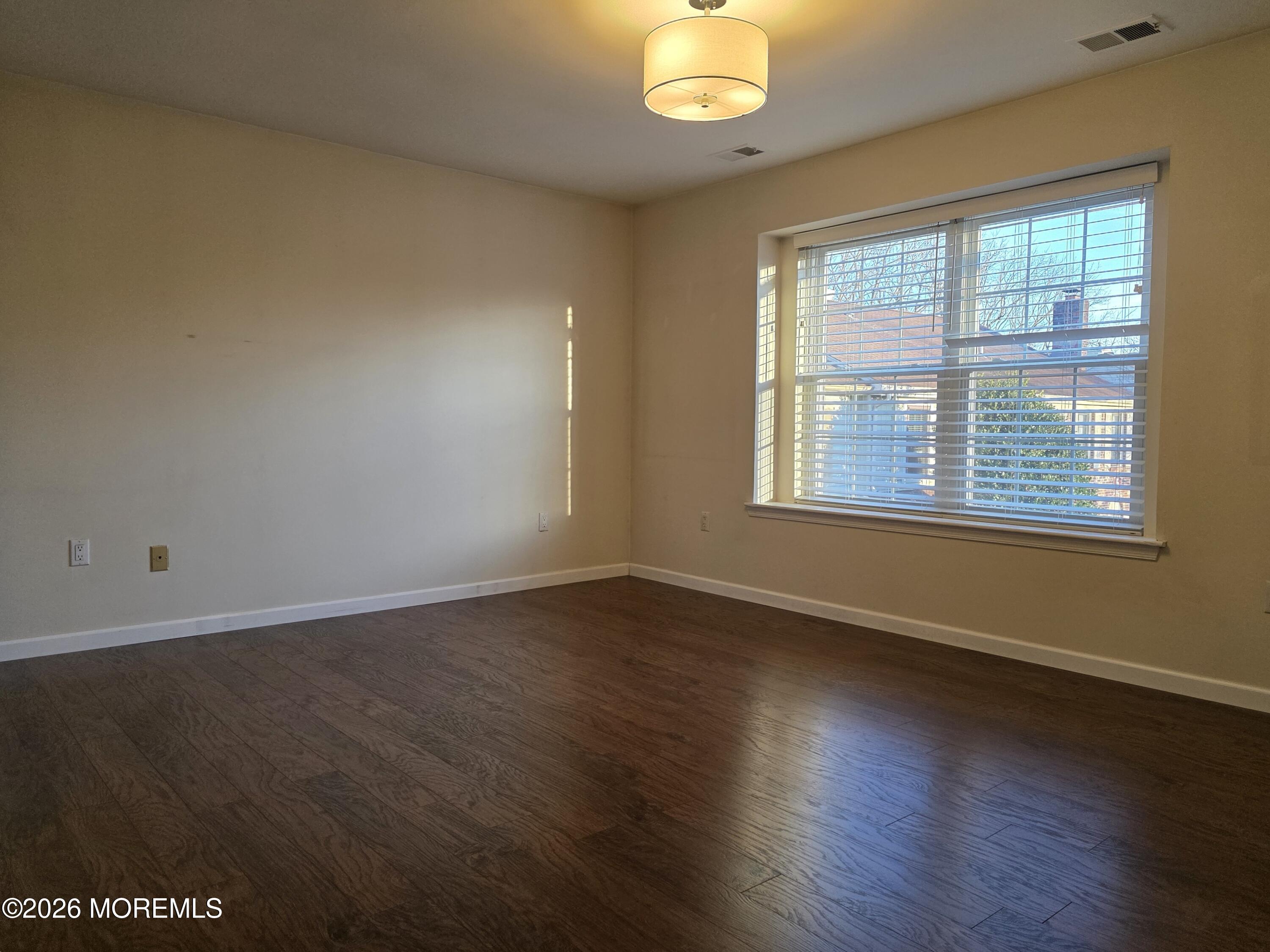 5 Claridge Court, Unit 4 Freehold, NJ 07728 - Photo 10 of 13 an empty room with wooden floor and windows