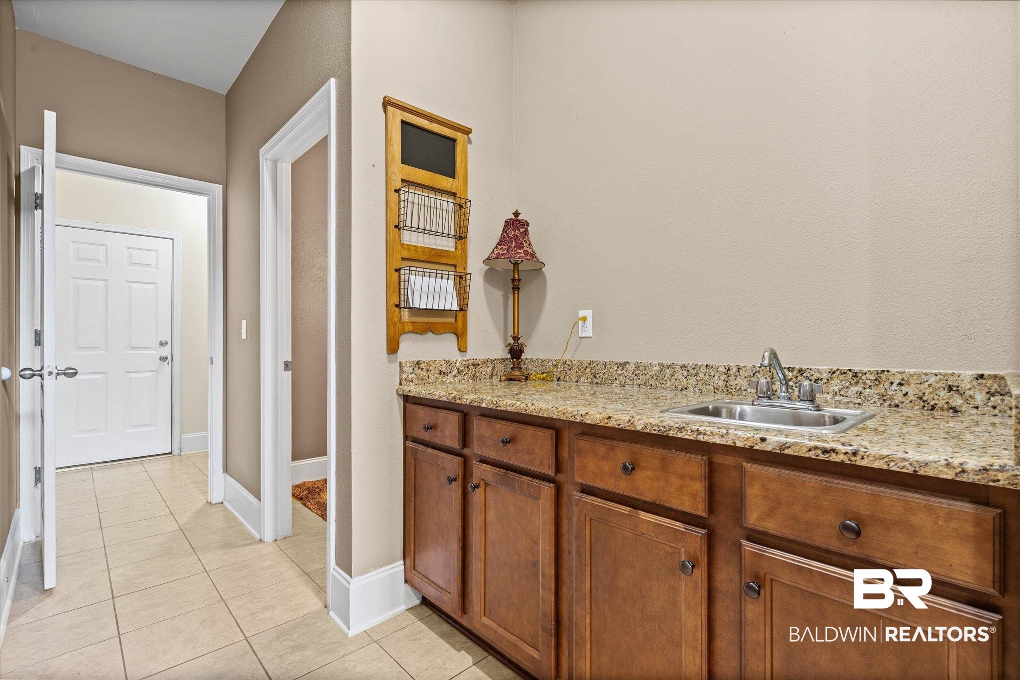 585 Sheffield Avenue Foley, AL 36535 - Photo 6 of 45 Utility area featuring a granite-look countertop, integrated stainless steel sink with chrome faucet, and wood-finish cabinetry