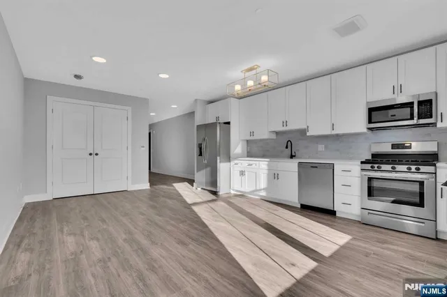 a kitchen with stainless steel appliances kitchen island granite countertop a stove a sink and a refrigerator