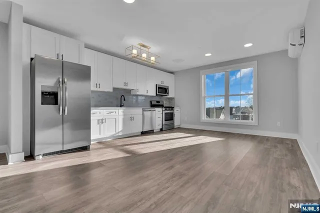 a view of kitchen stainless steel appliances wooden floor and window