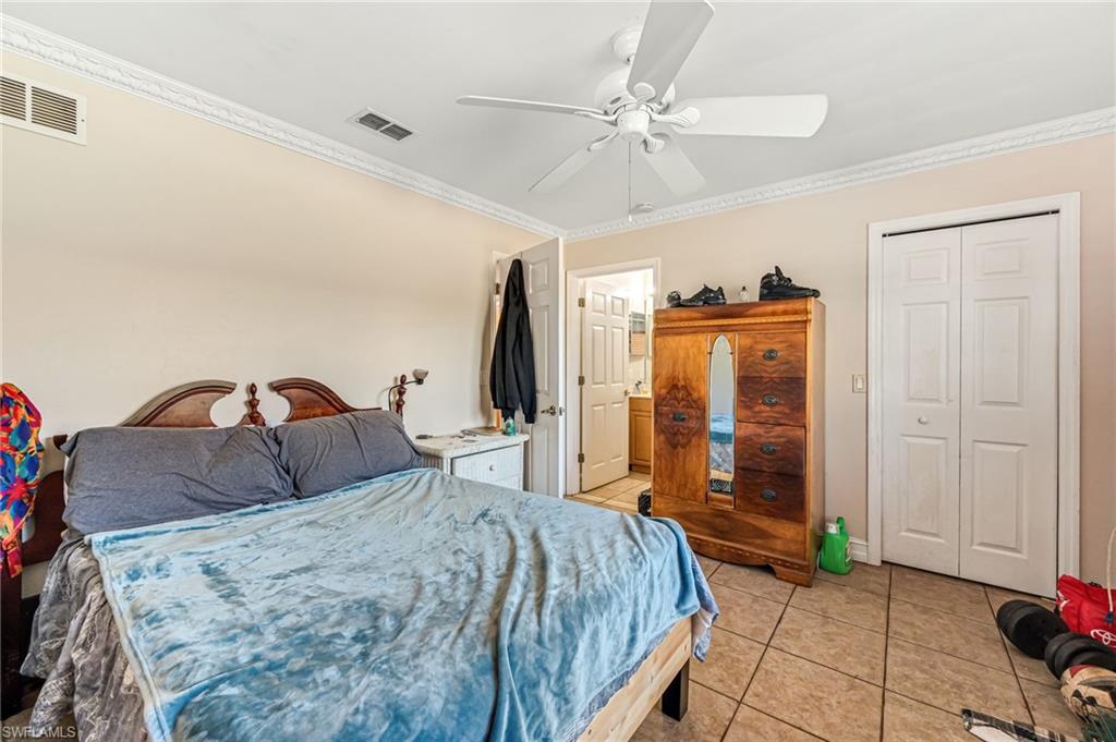 724 Pine Cone Lane Naples, FL 34104 - Photo 19 of 45 a bedroom with a bed and a chandelier