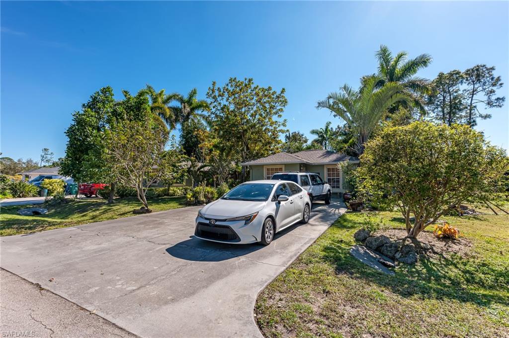 724 Pine Cone Lane Naples, FL 34104 - Photo 2 of 45 a view of a backyard with table and chairs under an umbrella