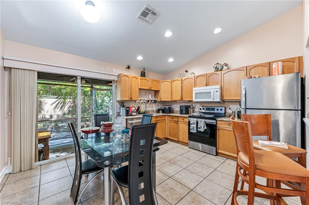 724 Pine Cone Lane Naples, FL 34104 - Photo 25 of 45 a kitchen with stainless steel appliances granite countertop table chairs refrigerator and microwave