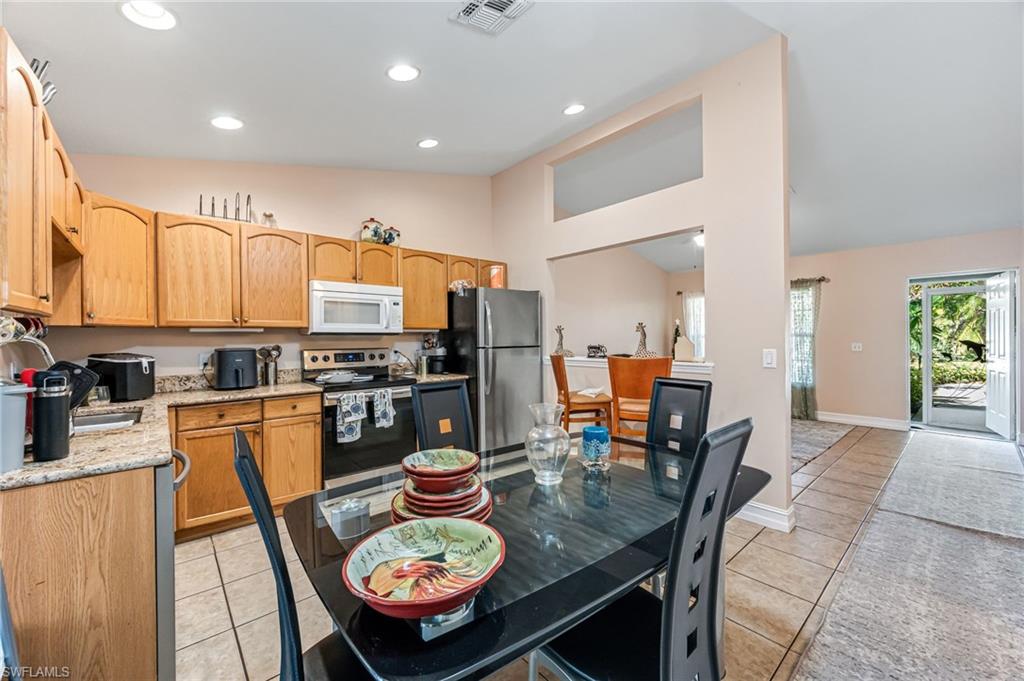 724 Pine Cone Lane Naples, FL 34104 - Photo 26 of 45 a kitchen with stainless steel appliances granite countertop a stove a sink a dining table and chairs