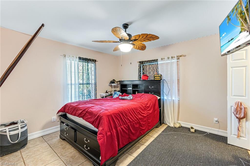 724 Pine Cone Lane Naples, FL 34104 - Photo 33 of 45 a bedroom with a bed and a chandelier