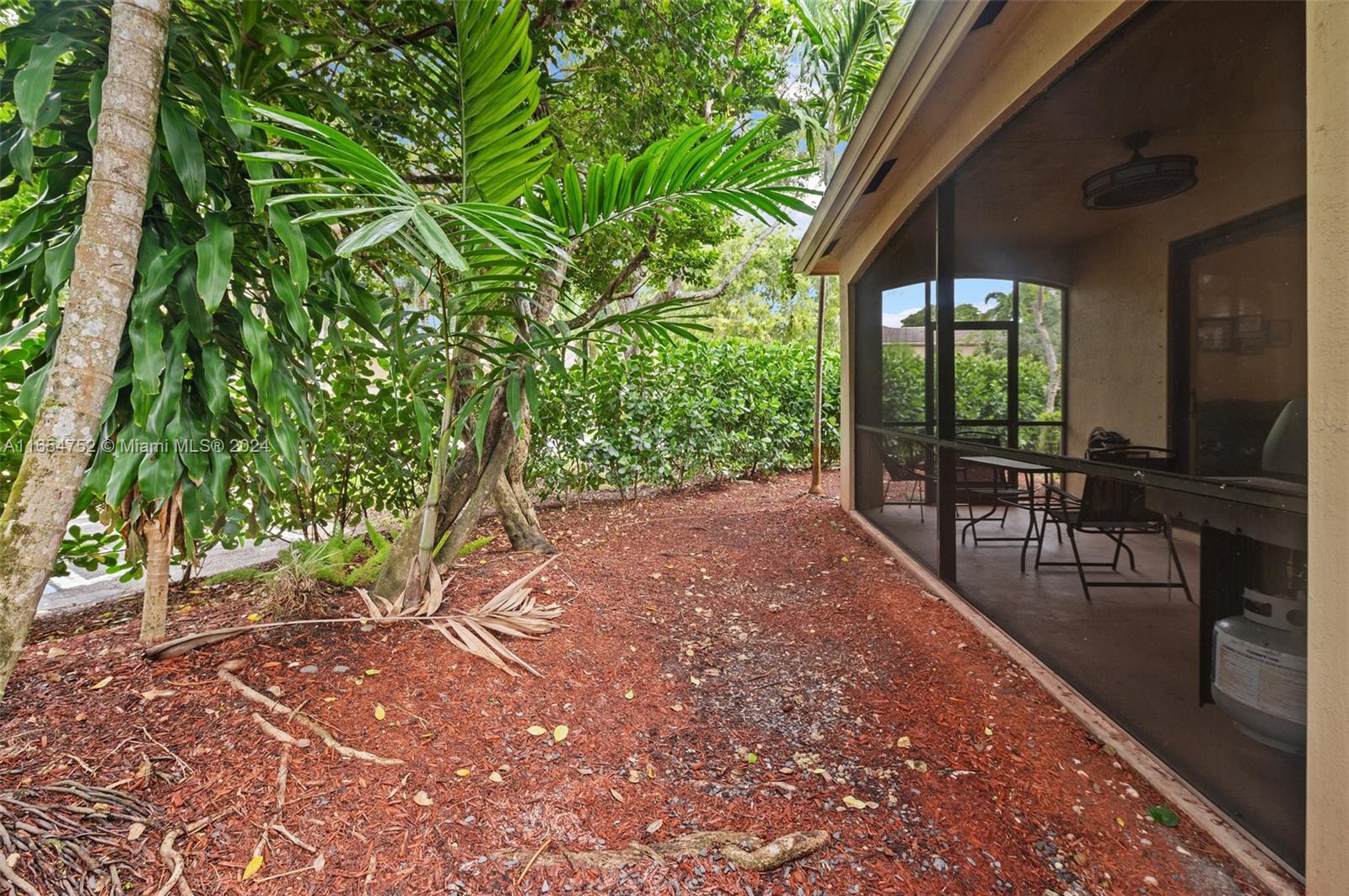 3822 Tree Top Drive Weston, FL 33332 - Photo 31 of 37 a view of a patio with table and chairs near a garden