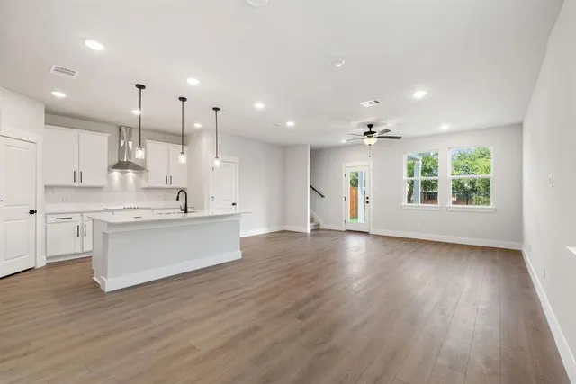 a large kitchen with stainless steel appliances granite countertop a large window a oven and white cabinets with wooden floors