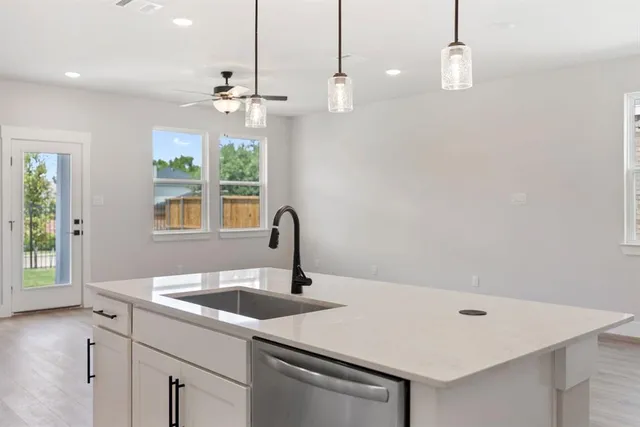 a kitchen with a sink a chandelier stainless steel appliances and windows