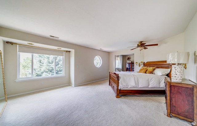 1273 Grayson Court Sandy, UT 84094 - Photo 15 of 27 Bedroom featuring light-colored carpeting, a large window with roller shades, and a circular accent window