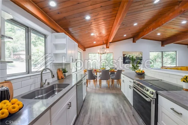a kitchen with granite countertop a sink a counter space stainless steel appliances and a large window