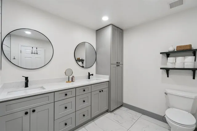 a bathroom with 2 sink a mirror and a toilet