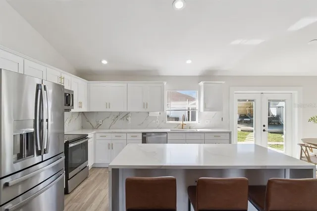 a kitchen with stainless steel appliances granite countertop a table chairs refrigerator and sink