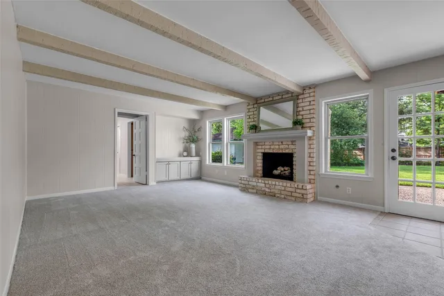 a view of an empty room with a fireplace and a window