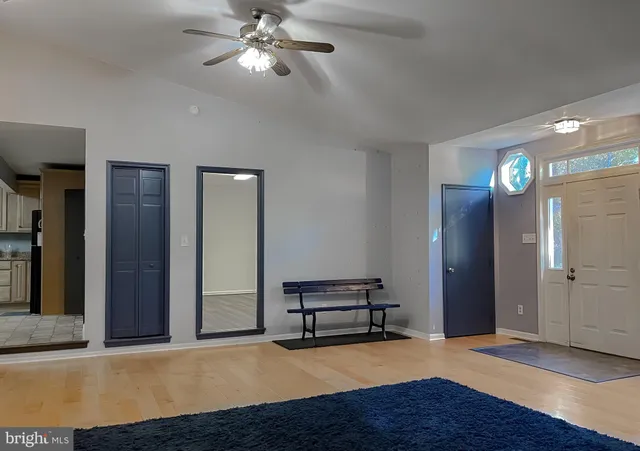 a view of an empty room with wooden floor and a ceiling fan