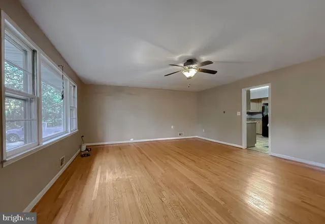 a view of an empty room with a window and wooden floor
