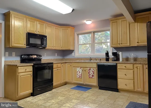 a kitchen with granite countertop wooden cabinets stainless steel appliances a window and a sink