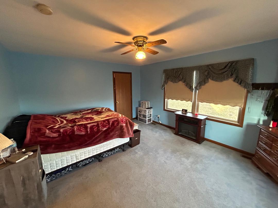 10598 North 3500W Road Manteno, IL 60950 - Photo 25 of 56 a spacious bedroom with a bed and a chandelier