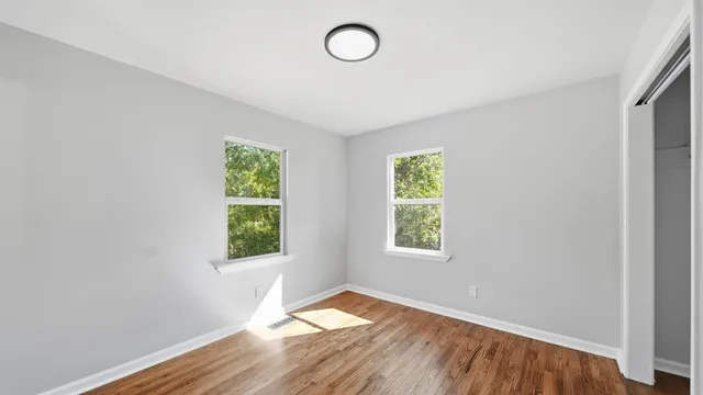 an empty room with wooden floor and windows