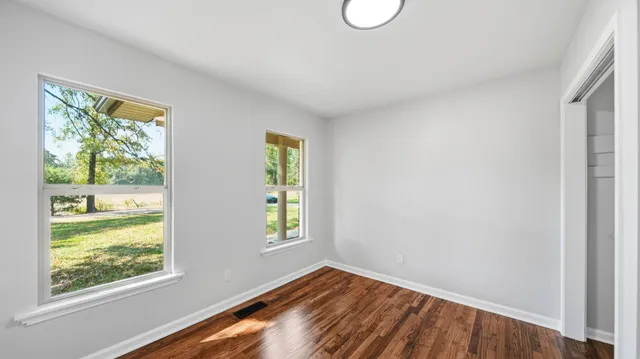 a view of an empty room with wooden floor and a window