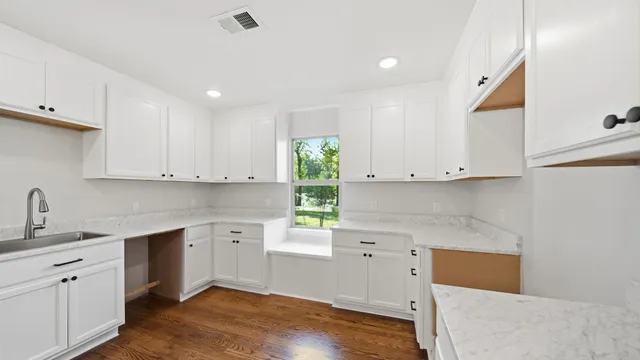a kitchen with white cabinets and window