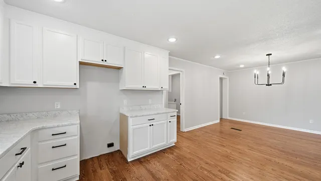 a view of a kitchen with white cabinets and wooden floor