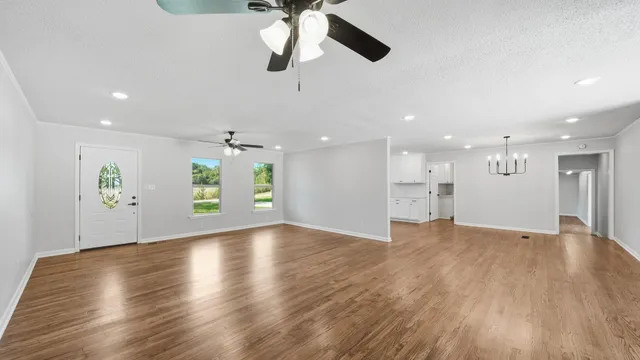 a view of an empty room with window and wooden floor